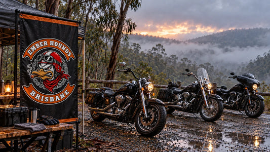 Ember Hounds Brisbane motorcycle club wet-weather rally staging area with a logo banner and parked V-twin cruisers in a misty Australian forest.