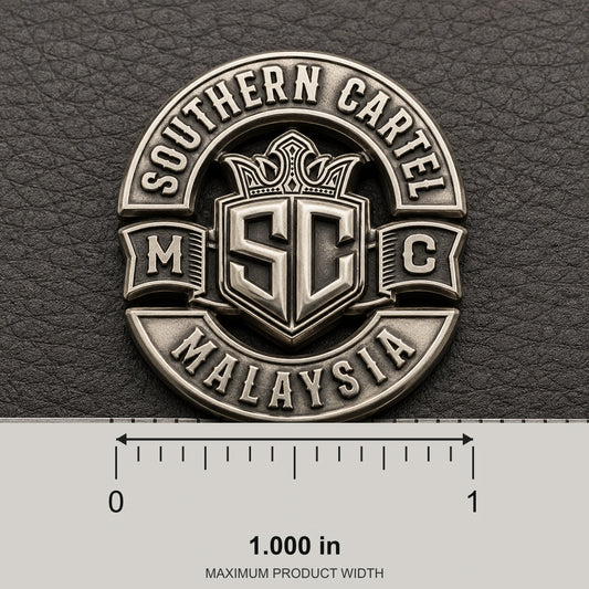 One-inch antique silver club pin beside a ruler and fingertip on a black leather workbench.