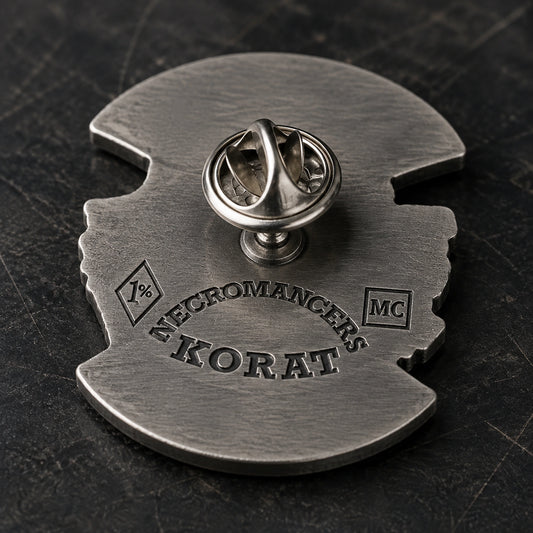 Rear of a Necromancers Korat motorcycle club pin showing a recessed back stamp, welded post and attached butterfly clutch.