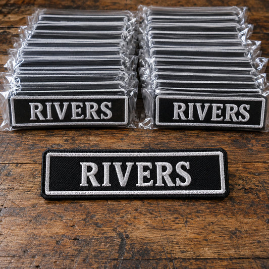 Approved motorcycle club name-bar sample beside a neatly packed complete chapter order ready for worldwide shipping, showing custom motorcycle club name bar patch options.