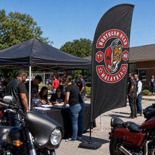 Charity Rides And Community Events: custom motorcycle club feather flag shown in daytime charity ride registration area with diverse adult volunteers and riders, family-friendly and no fundraising text.