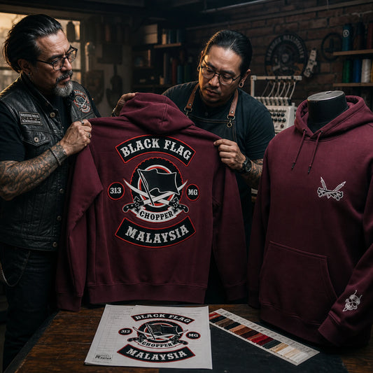 A club representative reviews an approved back-logo sample for a burgundy heavyweight motorcycle club hoodie.