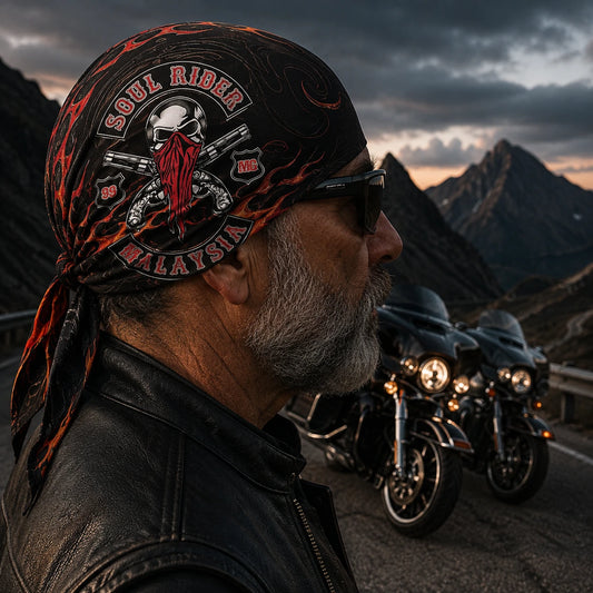 Custom motorcycle club bandana featuring the authorized SOUL RIDER2 identity in a mature road captain wearing the fitted headwrap at a mountain pass before dawn, touring motorcycles behind him.
