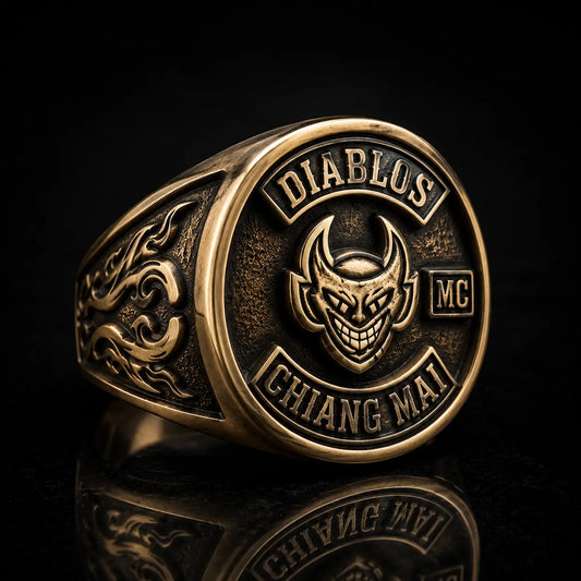 Custom motorcycle club signet ring with devil logo design in aged brass finish and deep sculpted metal relief.