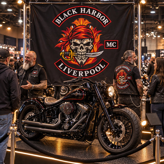 A complete custom club flag forms the backdrop for an American V-twin cruiser at an indoor motorcycle show.