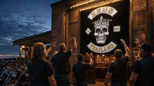 Motorcycle club members celebrate beneath an illuminated custom hanging flag that represents their shared identity.