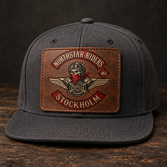 Flat-brim motorcycle club hat with a wide approved leather emblem.