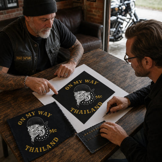 A motorcycle club road captain reviews a custom diamond flag proof and fabric sample at a clubhouse table.