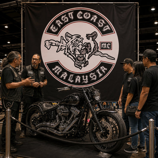 A custom club flag forms the backdrop for an American V-twin cruiser at an indoor motorcycle exhibition.