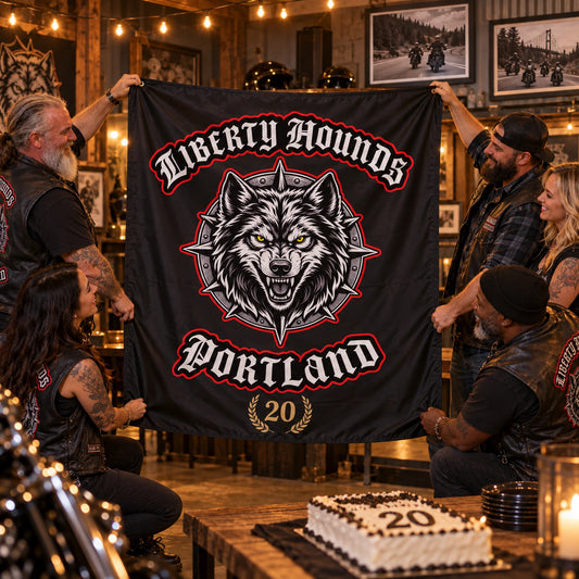 Adult motorcycle club members unveil a custom emblem flag during a warm clubhouse anniversary gathering.