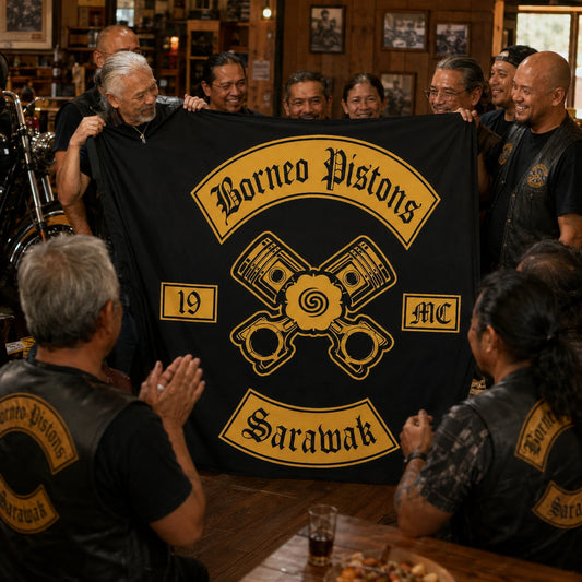 Adult motorcycle club members unveil a custom emblem flag during a warm clubhouse anniversary gathering.