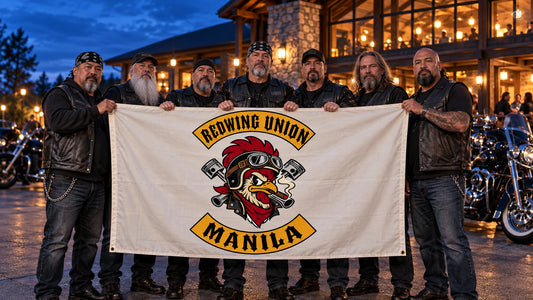 A motorcycle club crew holds a complete custom chapter flag beside V-twin cruisers at a blue-hour clubhouse gathering.