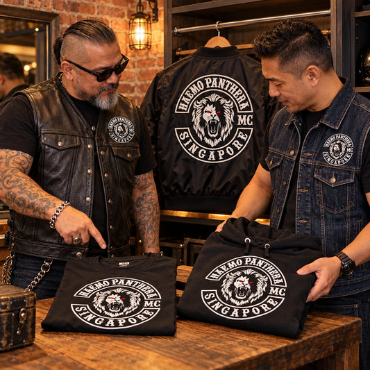 Motorcycle club members reviewing custom vests and apparel carrying an authorized club logo inside a clubhouse.