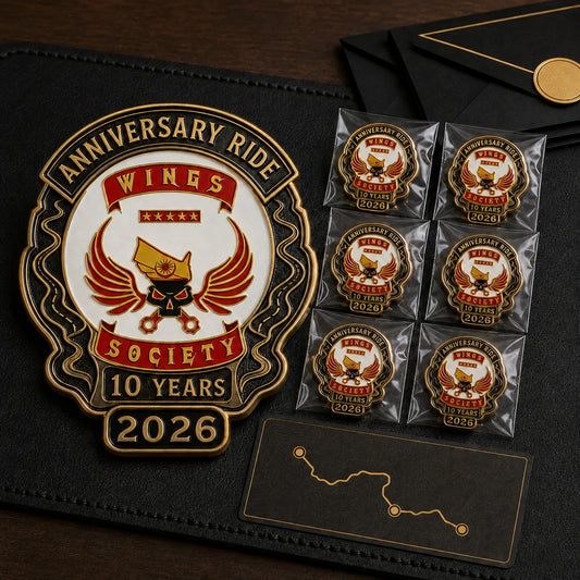 Wings Society motorcycle club 2026 anniversary ride badge displayed with matching packaged pins and a route card.