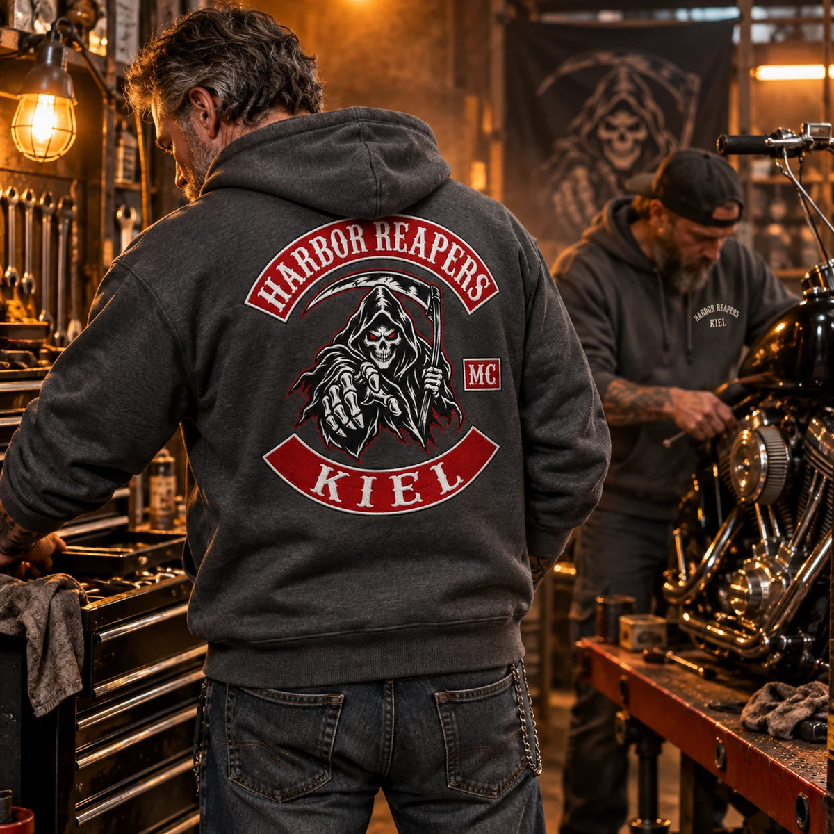 Dark gray hoodie in a working garage featuring a custom motorcycle club hoodie with authorized club artwork.