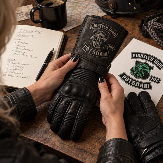 Black cowhide leather gauntlet glove with restrained motorcycle club branding in anniversary route-planning desk with a plain date notebook.