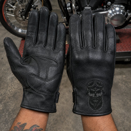 Black club gloves show palm seams beside a dorsal-facing glove with a charcoal engraved wrist emblem.