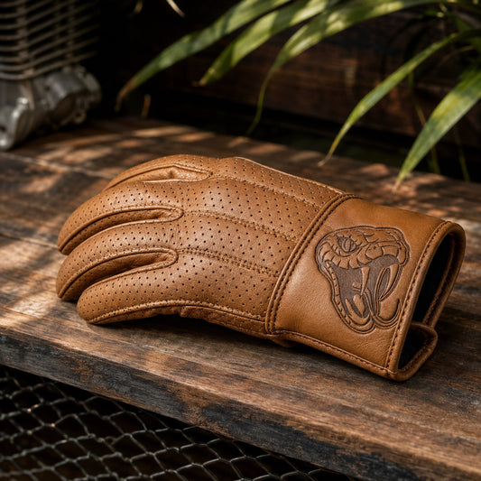 A perforated tan leather club glove has a solid wrist panel carrying the club emblem.