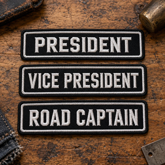 Motorcycle club officer title bars for President, Vice President and Road Captain, consistent traditional construction arranged on worn leather, showing custom motorcycle club name bar patch options.