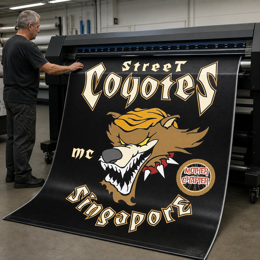 A print technician producing a durable custom motorcycle club banner with clear logo detail.