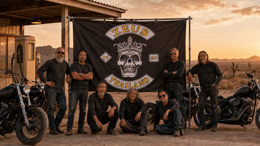 Proud motorcycle club riders posing with their finished custom event banner at sunset.