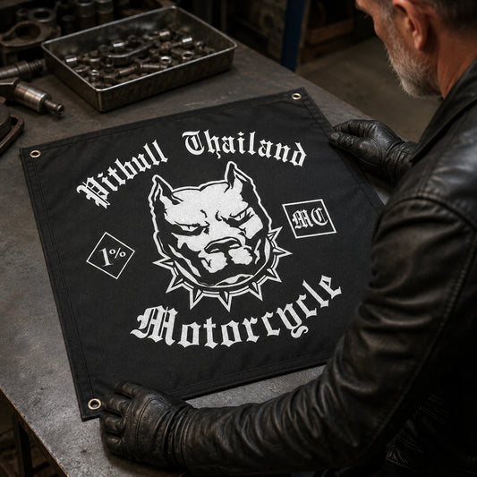 Motorcycle club rider inspecting a custom square club flag with reinforced seams and metal grommets on a workshop table.