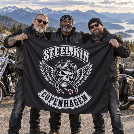 Mature V-twin riders hold a custom Steel Kin square club flag together at a mountain overlook.