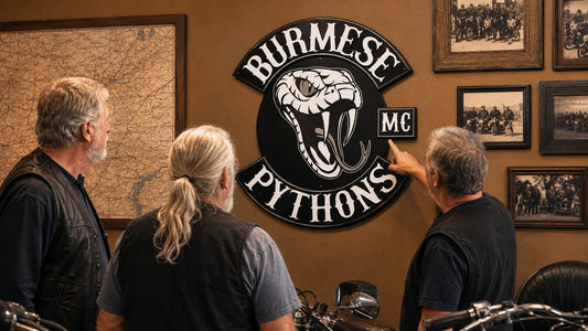 Motorcycle club members beside a custom chapter identity metal sign in their clubhouse heritage room.