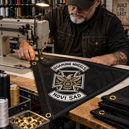 An experienced sewing operator finishes the reinforced edge of a custom motorcycle club triangle flag.