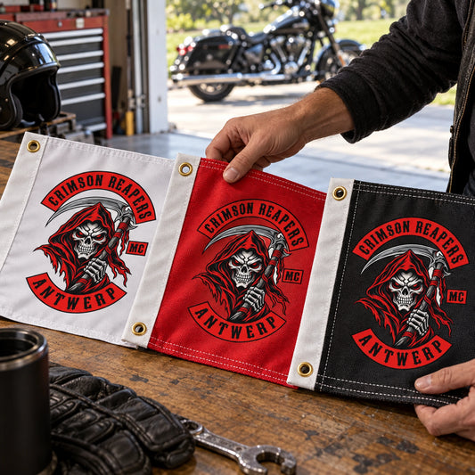 A product specialist compares durable custom motorcycle club flag fabrics and finished hems near an open garage door.