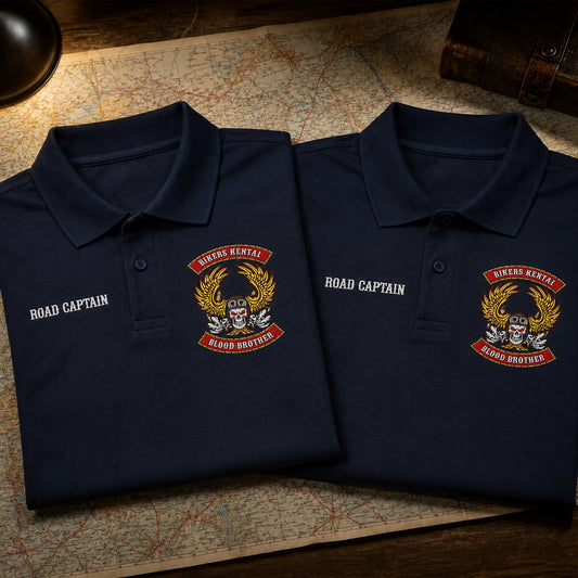 Close view of two navy Bikers Kental polo fronts on a map table, with ROAD CAPTAIN on the right chest and a club emblem on the left chest.