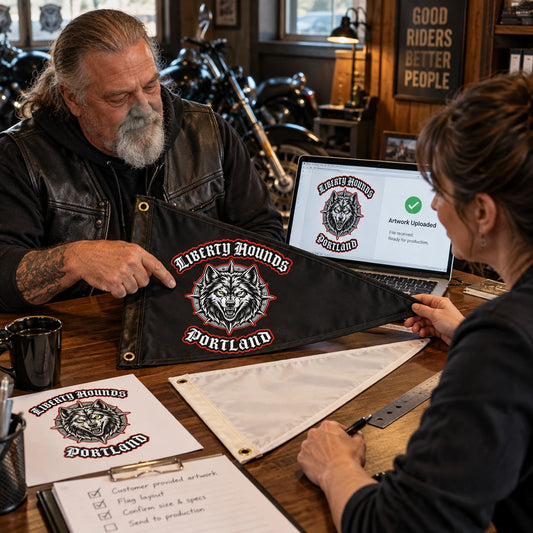 A motorcycle club president shares approved logo artwork with a designer at a clubhouse table.
