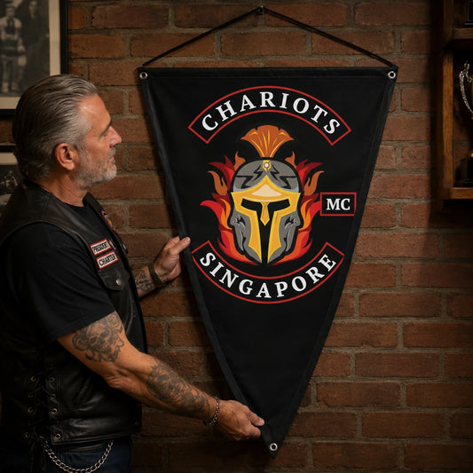 A motorcycle club officer presents a custom triangle flag centered on the club logo inside a clubhouse.