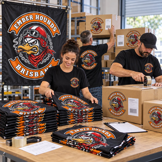 A fulfillment team prepares one sample flag and a boxed bulk order of custom motorcycle club flags.
