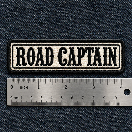 Standard 4 by 1 inch motorcycle name bar beside a precise metal ruler on dark denim for clear scale, showing custom motorcycle club name bar patch options.
