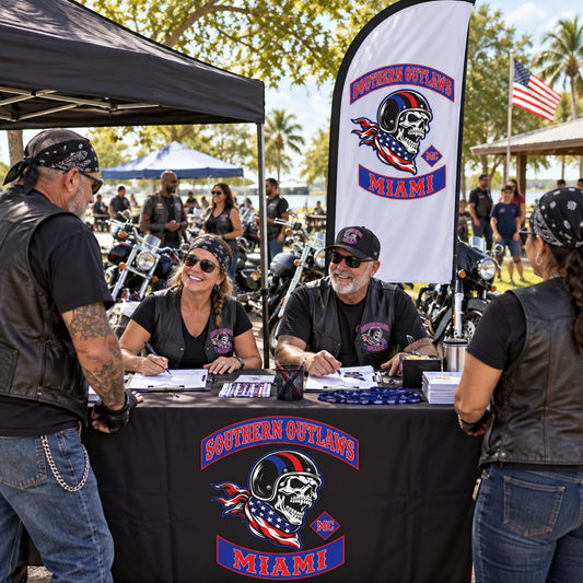 Charity Rides And Community Events: custom motorcycle club feather flag shown in daytime charity ride registration area with diverse adult volunteers and riders, family-friendly and no fundraising text.