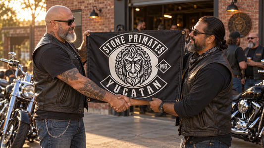 Two motorcycle club representatives exchanging a custom club flag outside a brick clubhouse.