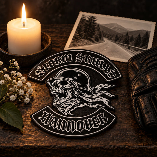 Motorcycle club memorial anniversary patch featuring the authorized Storm Skulls Hannover identity in a respectful candlelit still life with old ride photo.