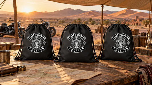 Stone Primates Yucatan motorcycle club drawstring bags arranged on a fixed-HQ gear custody table in a desert rally setting