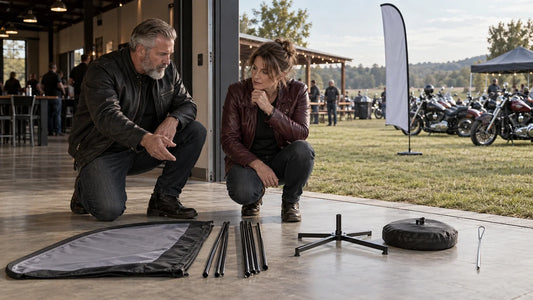Two mature motorcycle club organizers compare feather-flag bases at indoor and outdoor event surfaces.