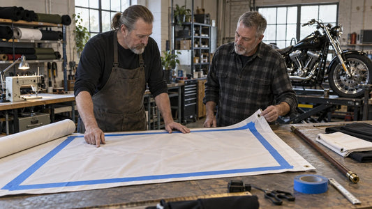 Two mature motorcycle club organizers compare sleeve, grommet and rod margins on a flag template.