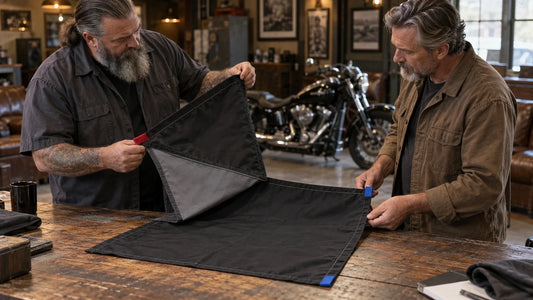 Two mature motorcycle club organizers compare the front and back of a two-sided flag sample.
