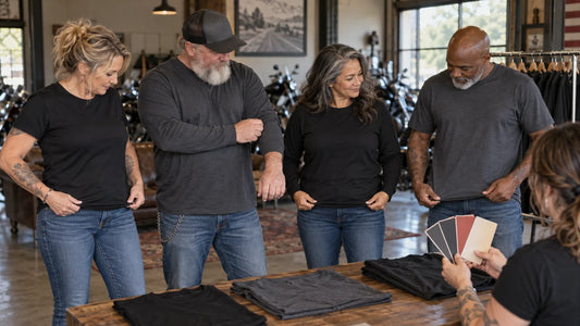 Four mature motorcycle club riders compare physical T-shirt sizes during a controlled clubhouse fitting session.