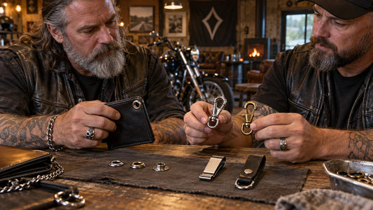 Two mature motorcycle club riders compare wallet eyelets, clasp gates and belt-side attachments at a workbench.