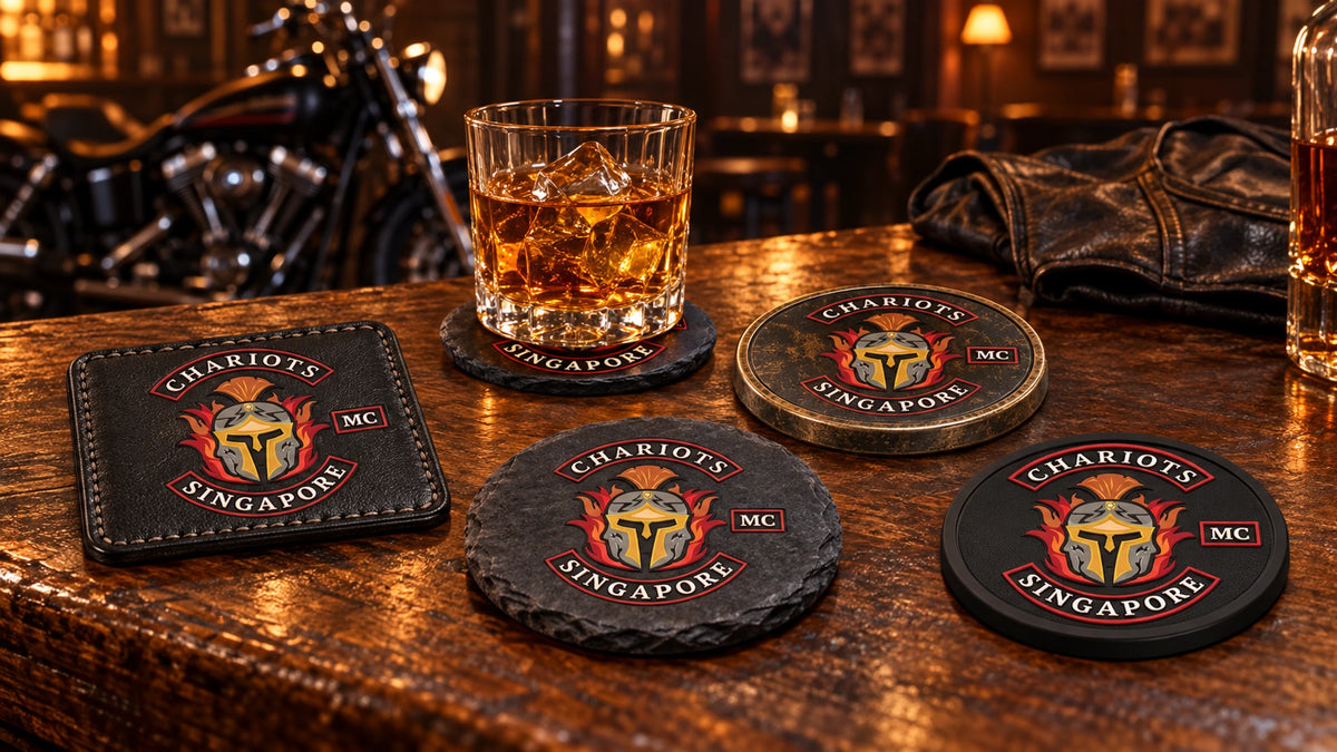 Leather, slate, metal and PVC motorcycle club coasters arranged on a dark clubhouse bar.