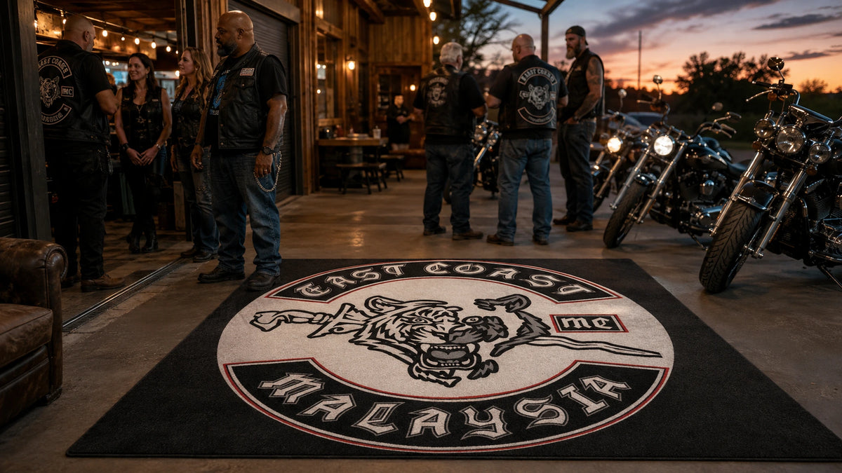 Mature motorcycle club members gather around a custom logo rug at a clubhouse with American V-twin motorcycles.