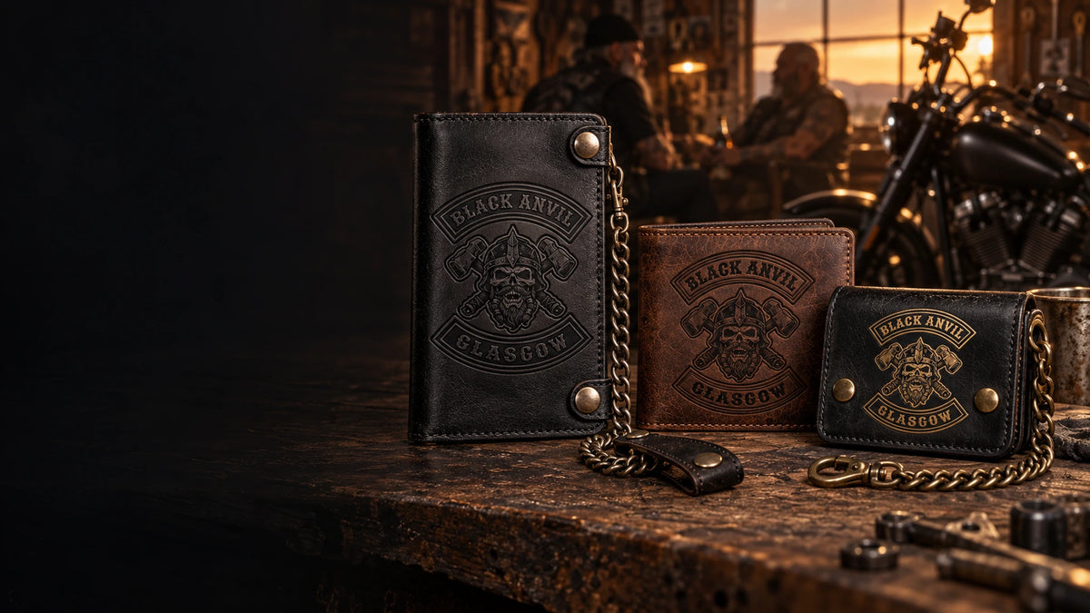 Custom Black Anvil Glasgow motorcycle club wallets showing debossed, laser-engraved and antique-brass leather finishes beside a V-twin motorcycle.