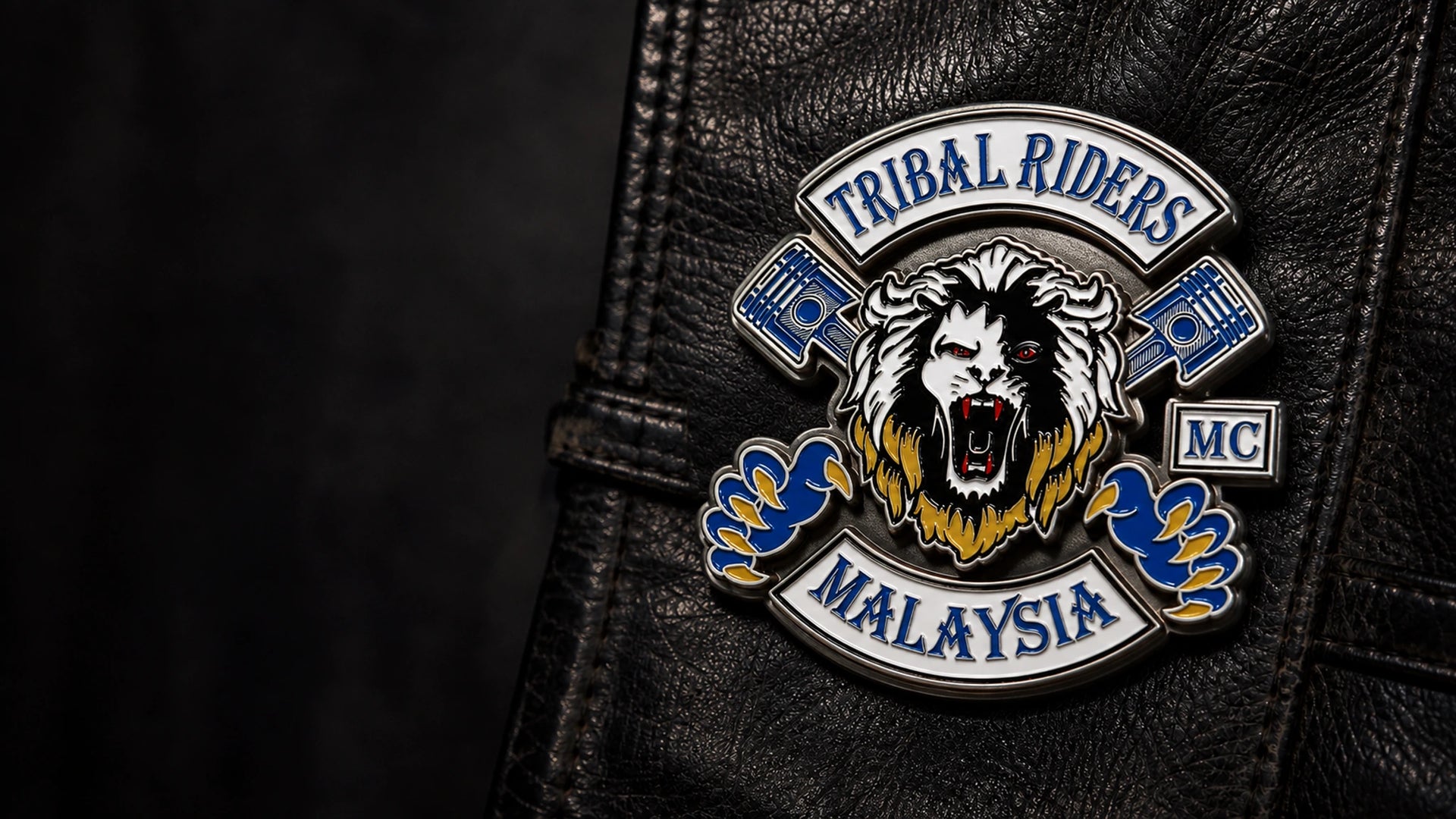 Colorful three-dimensional Tribal Riders motorcycle club enamel pin attached to a black leather riding vest.