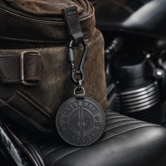 Custom motorcycle club carabiner keychain attached to a rugged riding bag with an authorized logo.