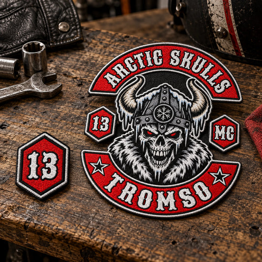 Charcoal embroidered diamond patch displaying the fictional number 27 on a workshop bench for a motorcycle club.